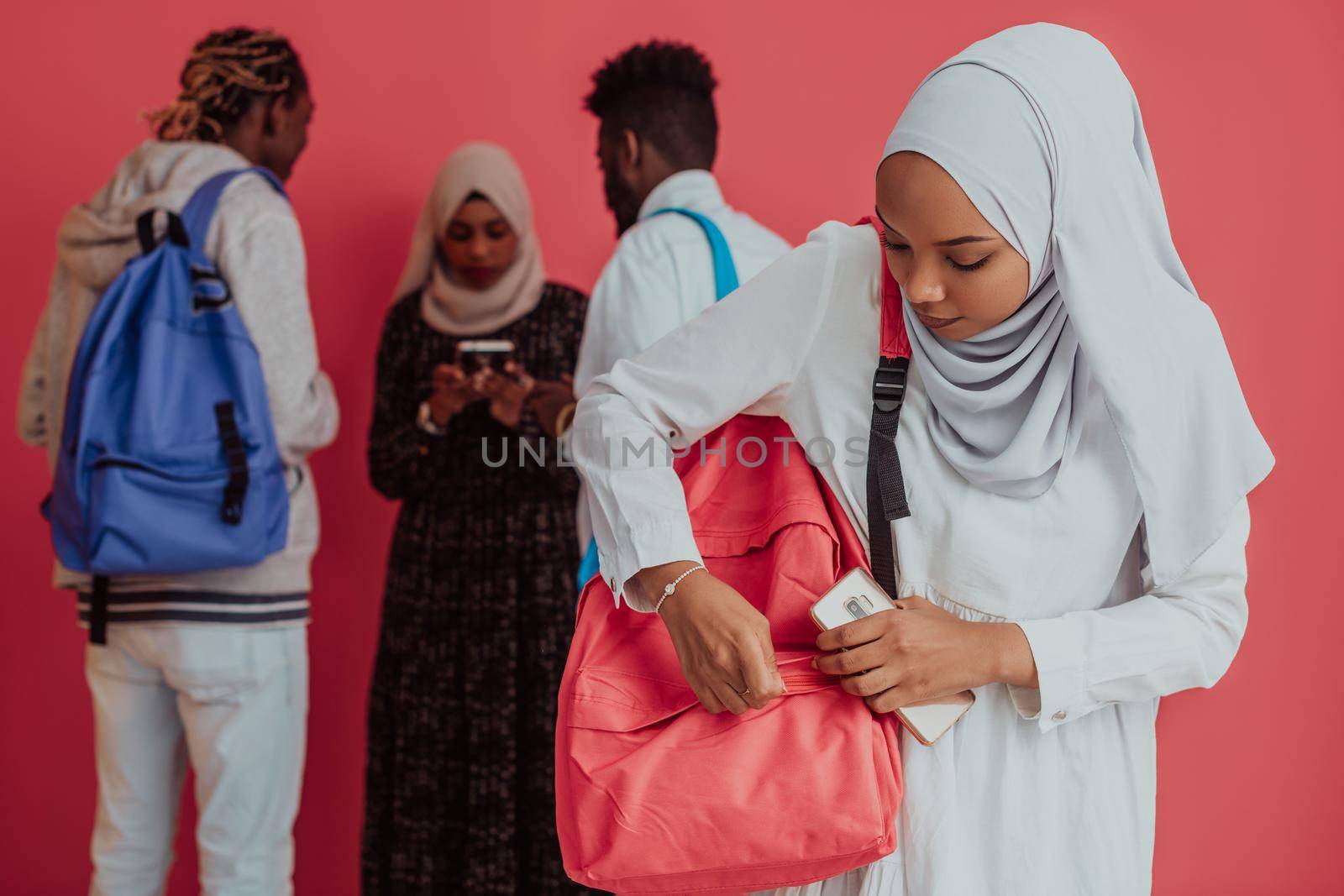 A group of African Muslim students with backpacks posing on a pink background. the concept of school education. by dotshock
