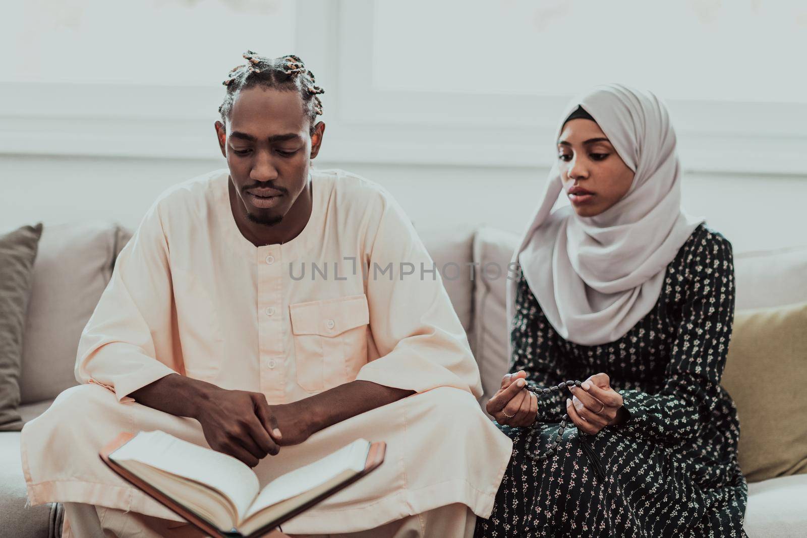 African Muslim couple at home in Ramadan reading Quran holly Islam book. by dotshock