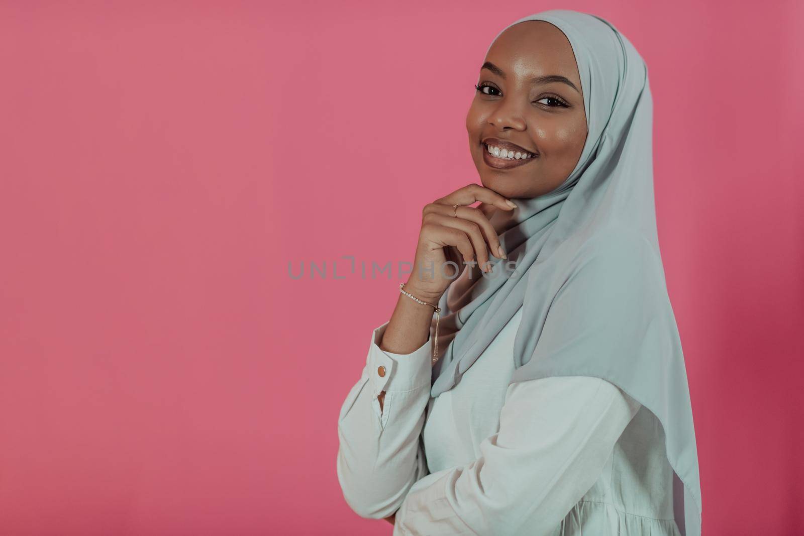 Portrait of young modern muslim afro beauty wearing traditional islamic clothes on plastic pink background. Selective focus. High quality photo