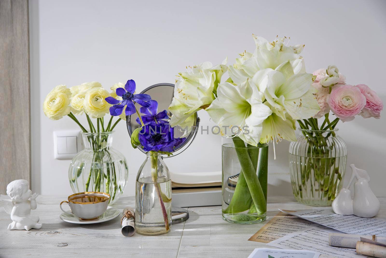Moscow, Russia - 14 December 2020, A bouquet of white roses in a round glass vase, a bouquet of white amaryllis, a cup of tea, a figurine on the table. Decoration of the kitchen. Rose Playa blanca