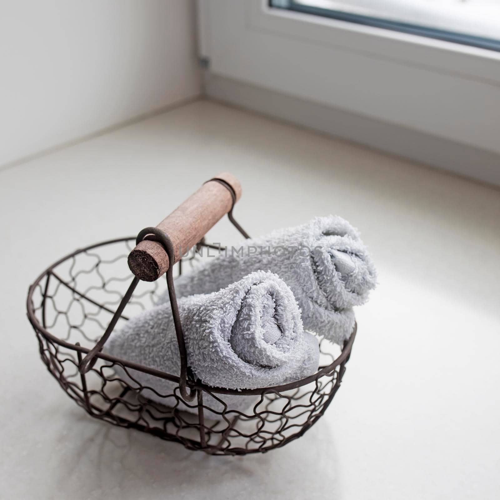 rolled towels in metal basket at clean bathroom by elenarostunova
