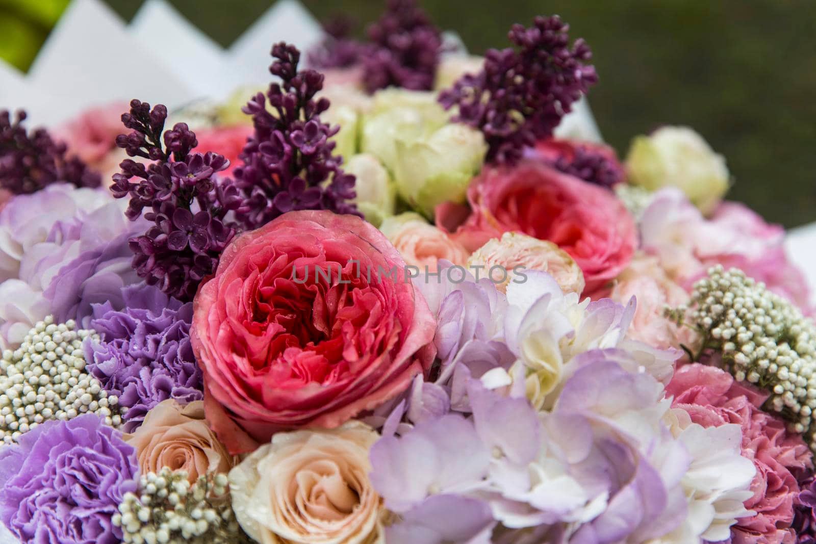 Wedding bouquet of tree pink peony, purple carnations, blue hydrangea, lilac, wrapped in craft paper by elenarostunova