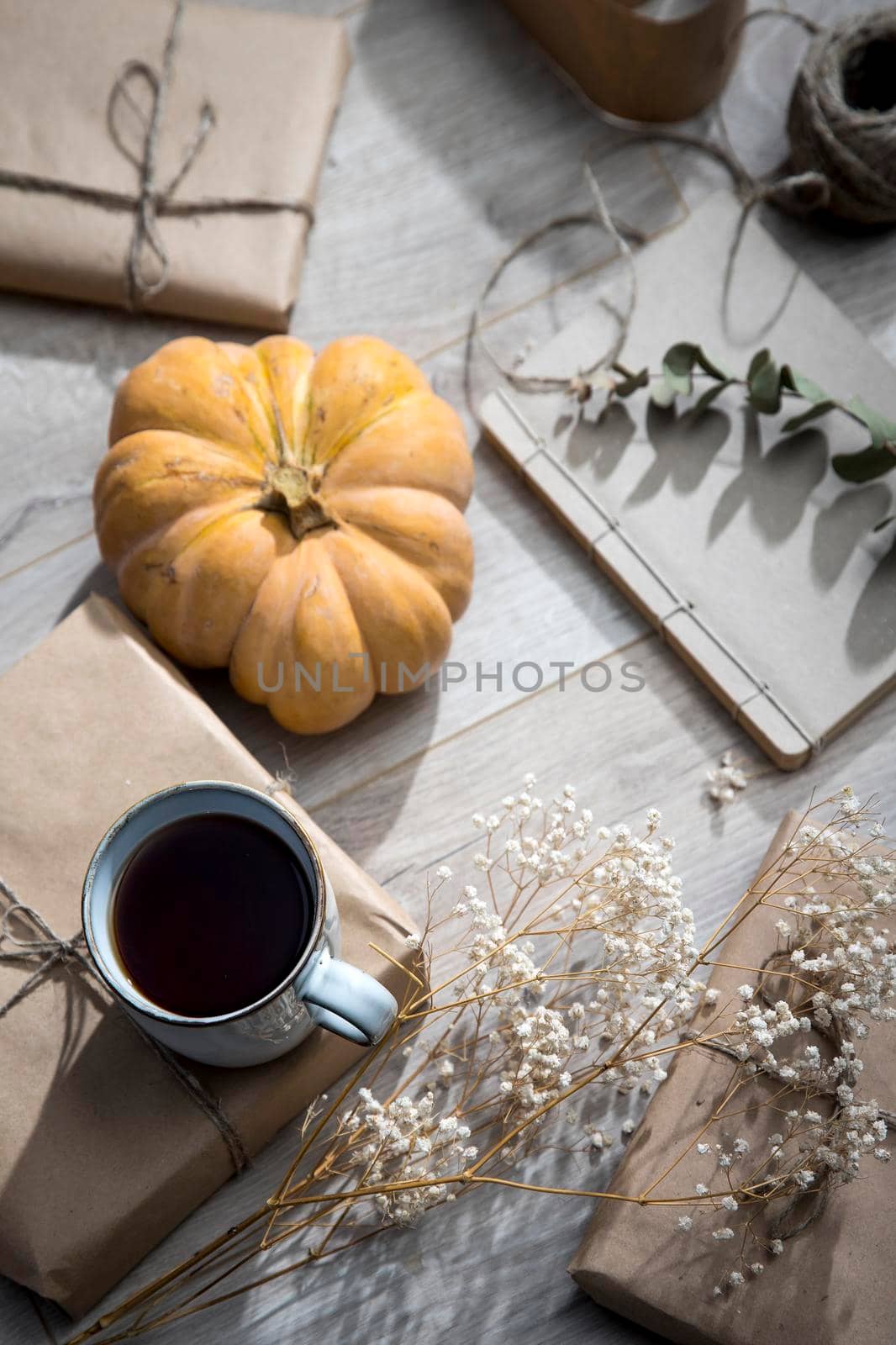 Packaged and bandaged gifts, pumpkins, a cup of tea and dried plants are on the table. Preparing for the birthday. Grunge
