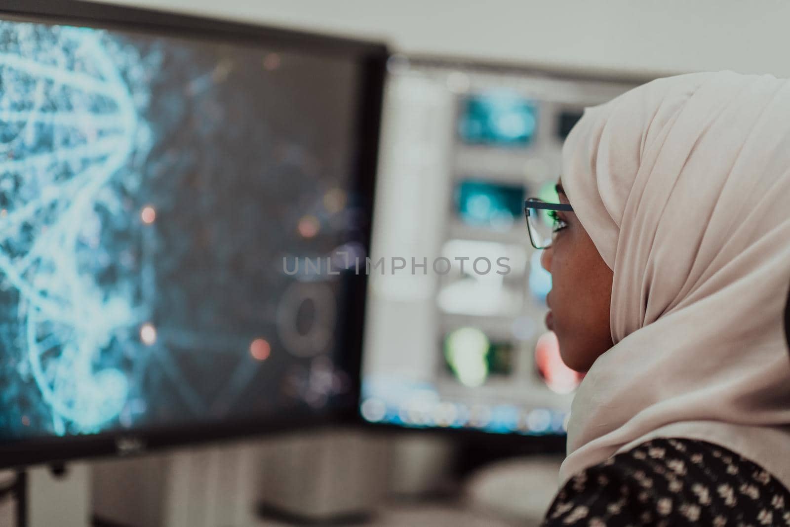 Young Afro-American modern Muslim businesswoman wearing a scarf in a creative bright office workplace with a big screen. High-quality photo