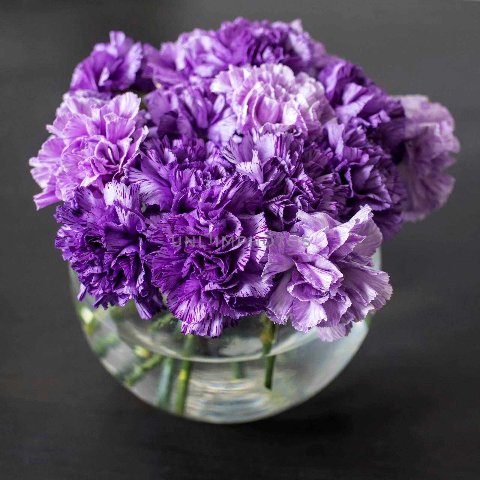 Bridal bouquet of lilac carnations in a round glass vase as table decoration