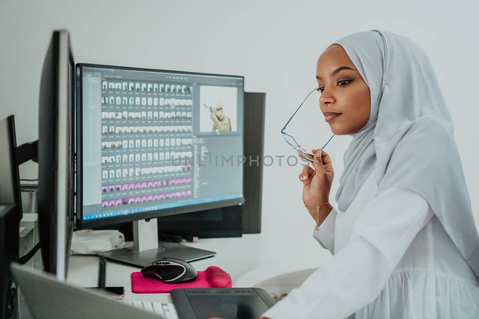 Young Afro-American modern Muslim businesswoman wearing a scarf in a creative bright office workplace with a big screen. High-quality photo