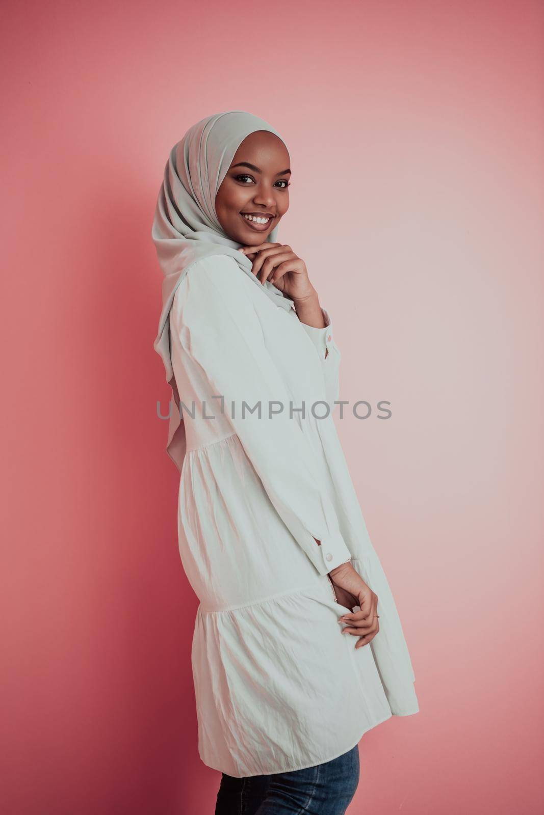 Portrait of young modern muslim afro beauty wearing traditional islamic clothes on plastic pink background. Selective focus. High quality photo