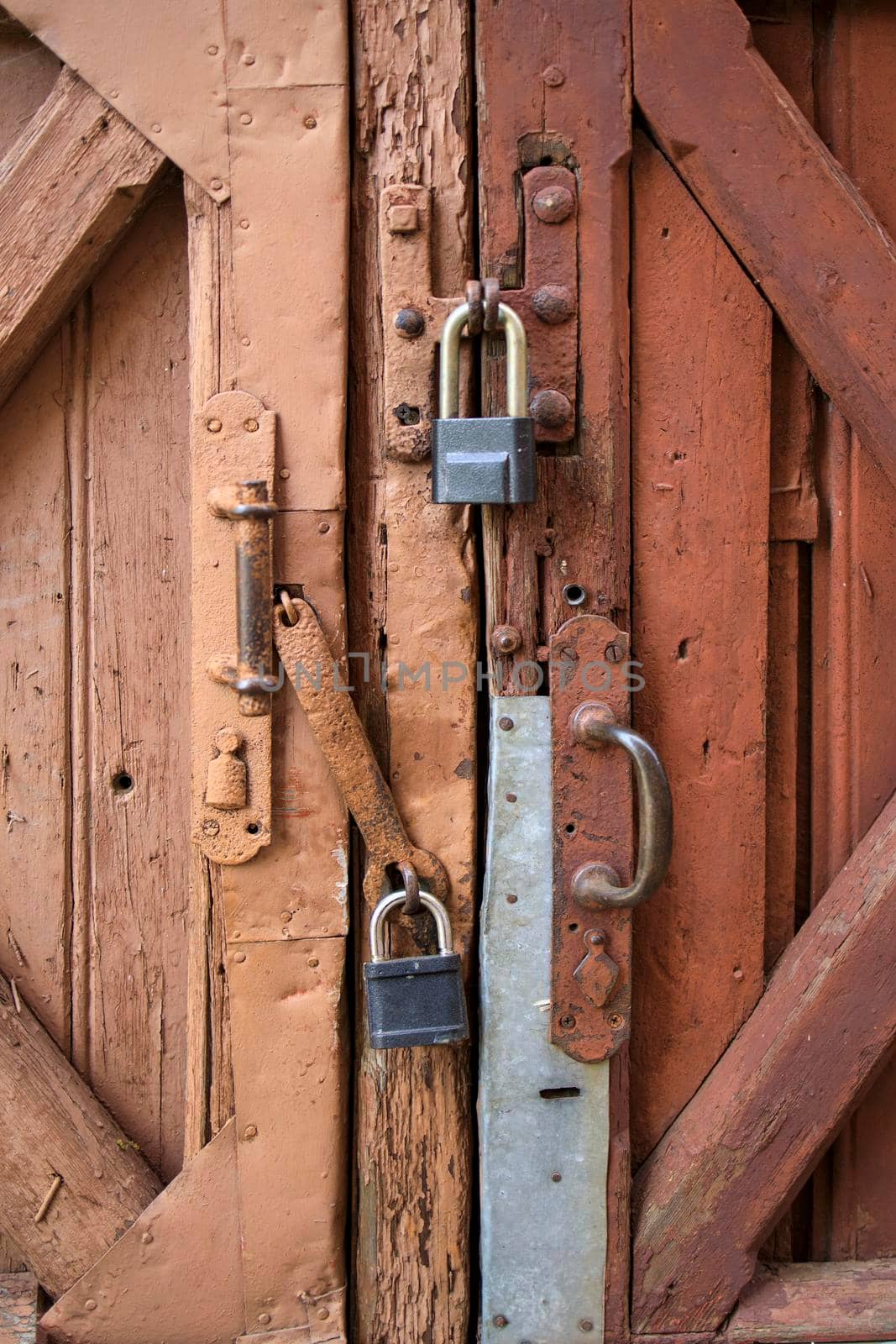Old barn doors, with peeling paint, with two large metal locks on them. Pattern