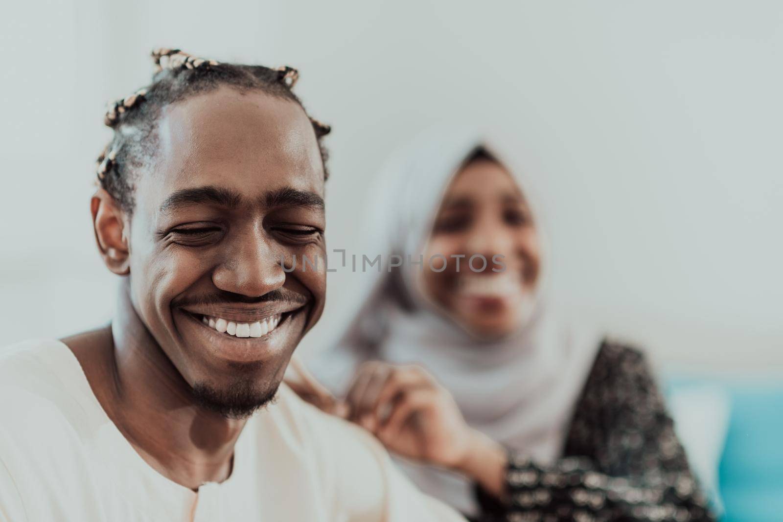 A young Muslim couple has a romantic time at home while the woman makes the hairstyle for her husband female wearing traditional Sudan Islamic hijab clothes. by dotshock