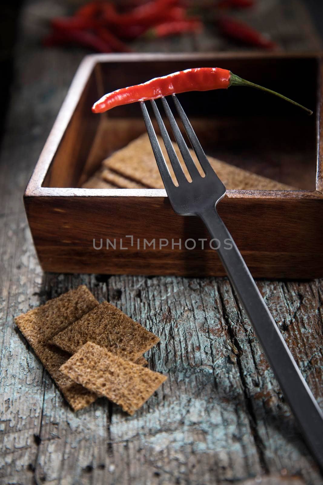 Hot chili peppers on a fork in a wooden mango tree box on a wooden bench. Copy space.Top view