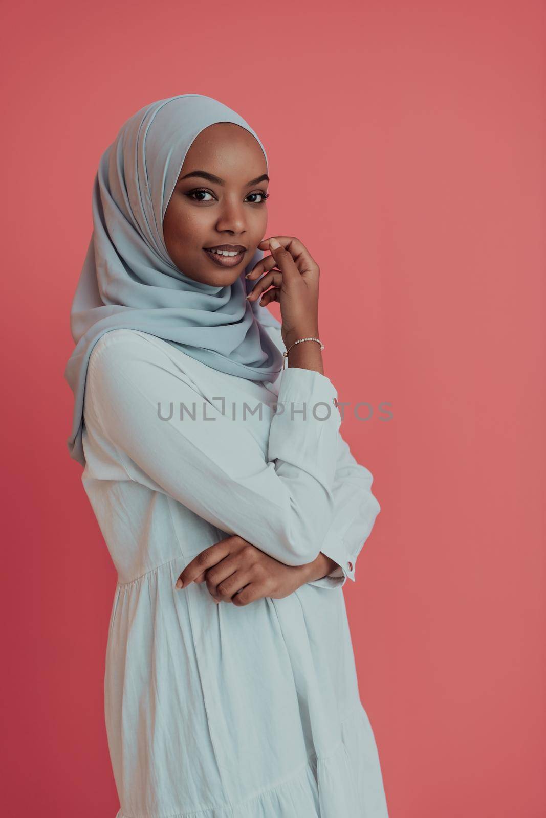 Portrait of young modern Muslim afro beauty wearing traditional Islamic clothes on plastic pink background. Selective focus. High-quality photo