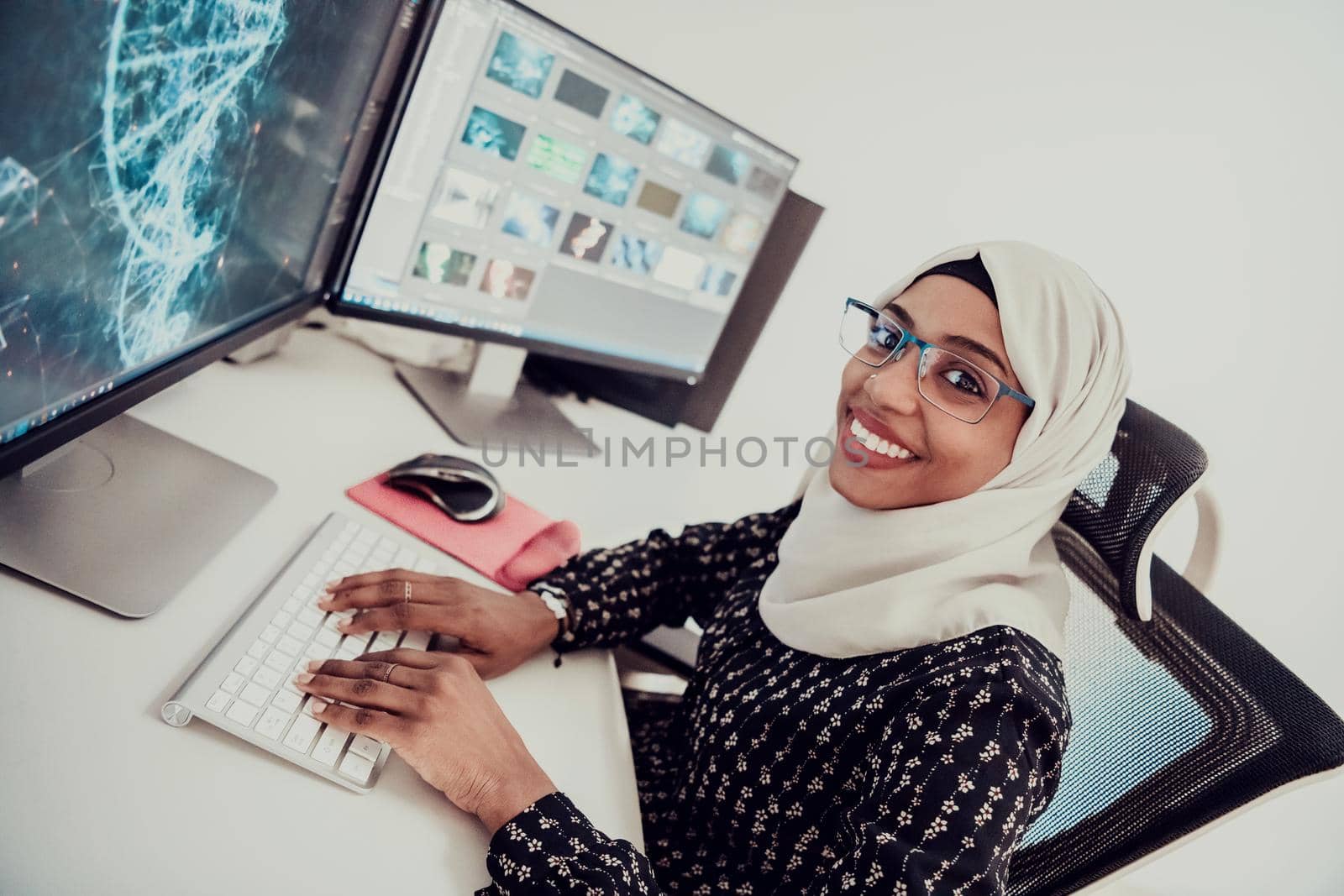 Young Afro-American modern Muslim businesswoman wearing a scarf in a creative bright office workplace with a big screen. High-quality photo