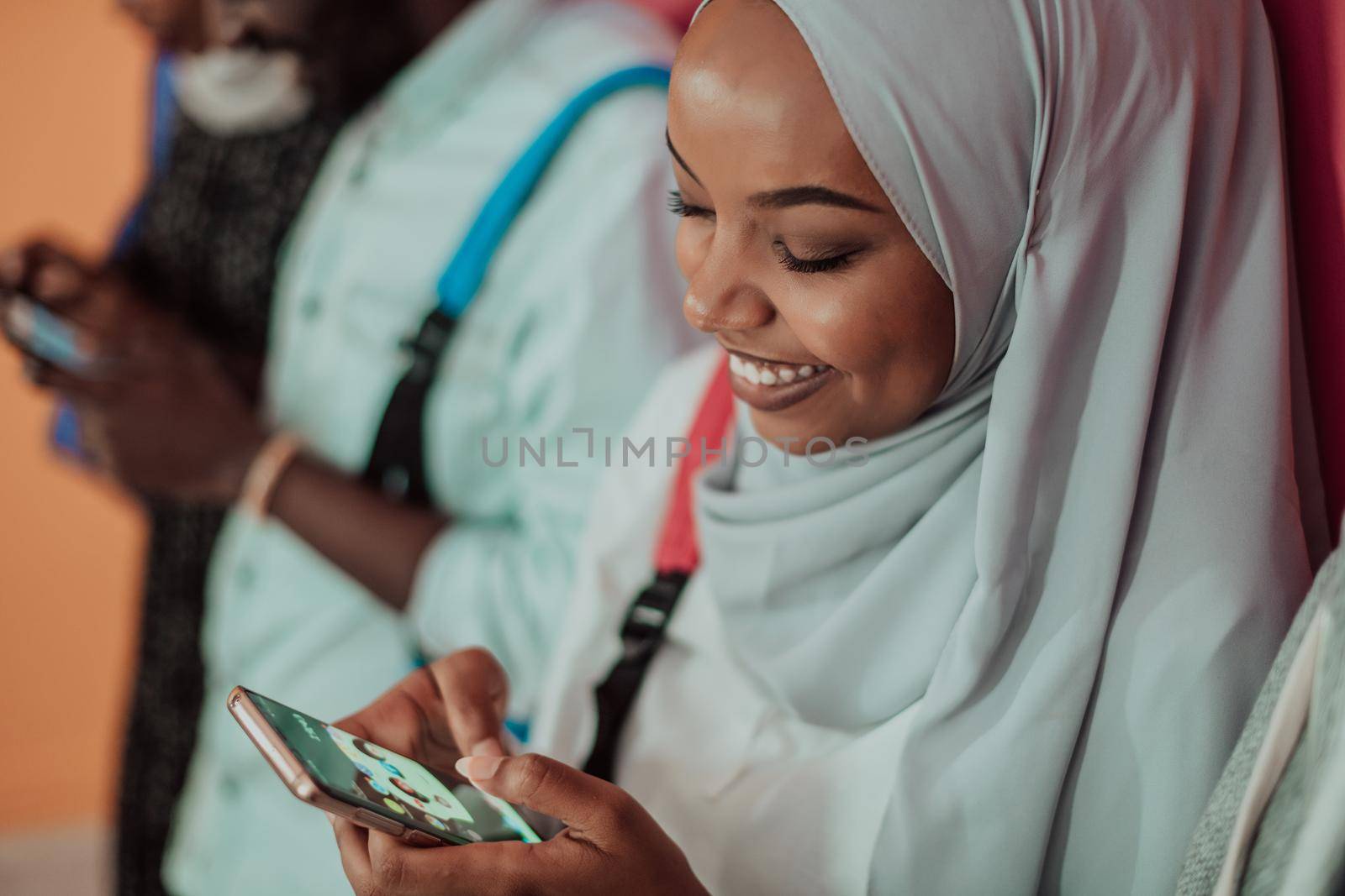 A group of African Muslim students use smartphones while standing in front of a yellow background by dotshock