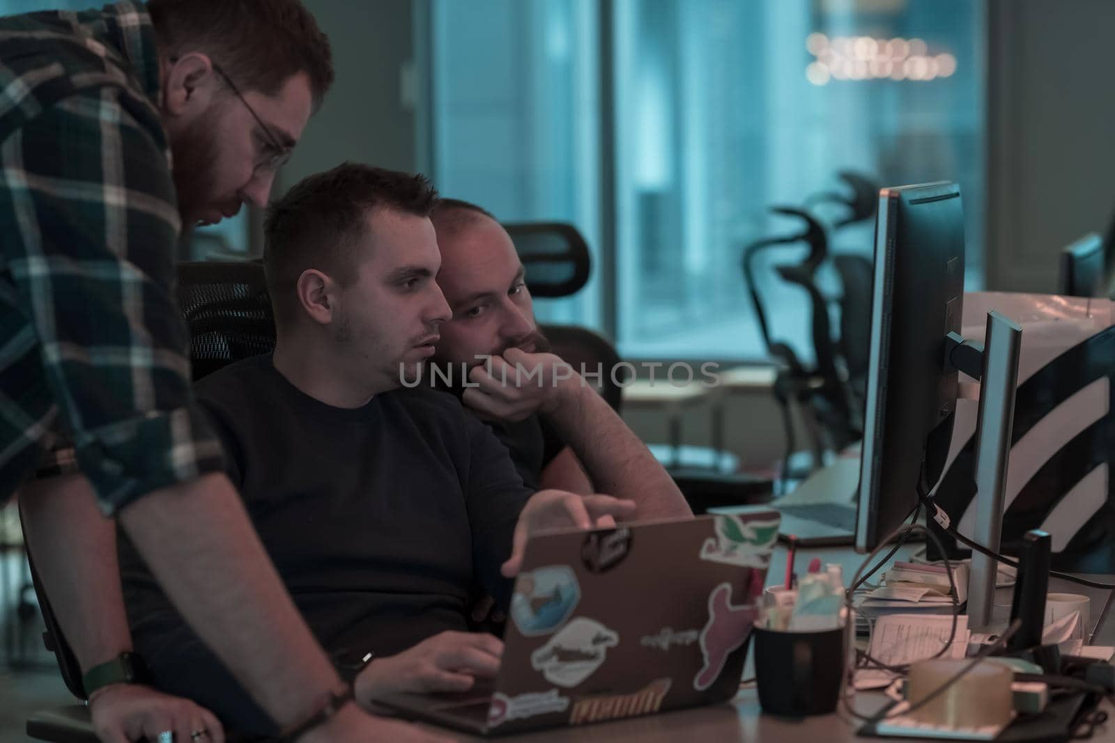 A photo of three men staring intently at a computer while sitting in a modern office. Selective focus by dotshock