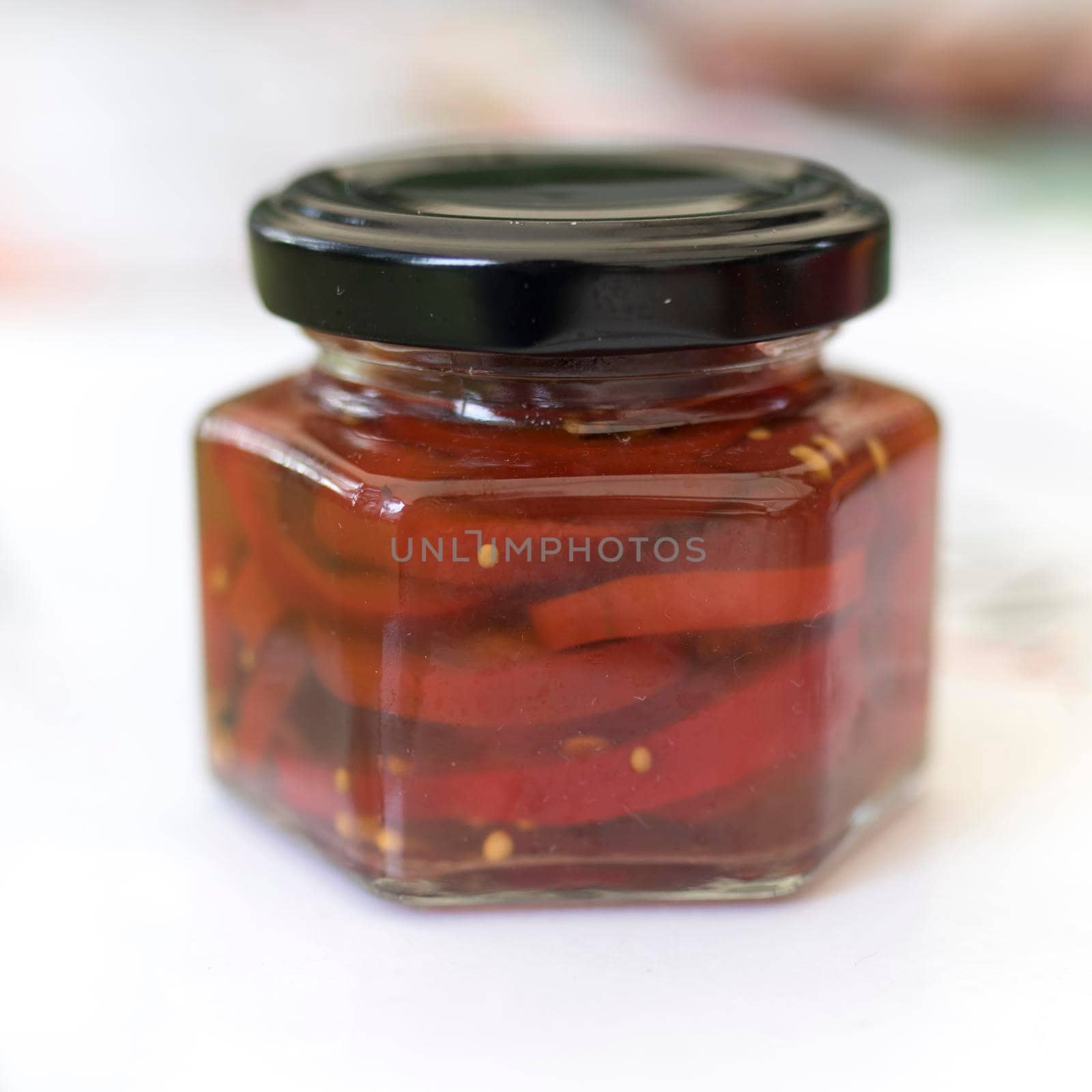 red pickled peppers with spices and different pickles in a jar for sale. Square frame