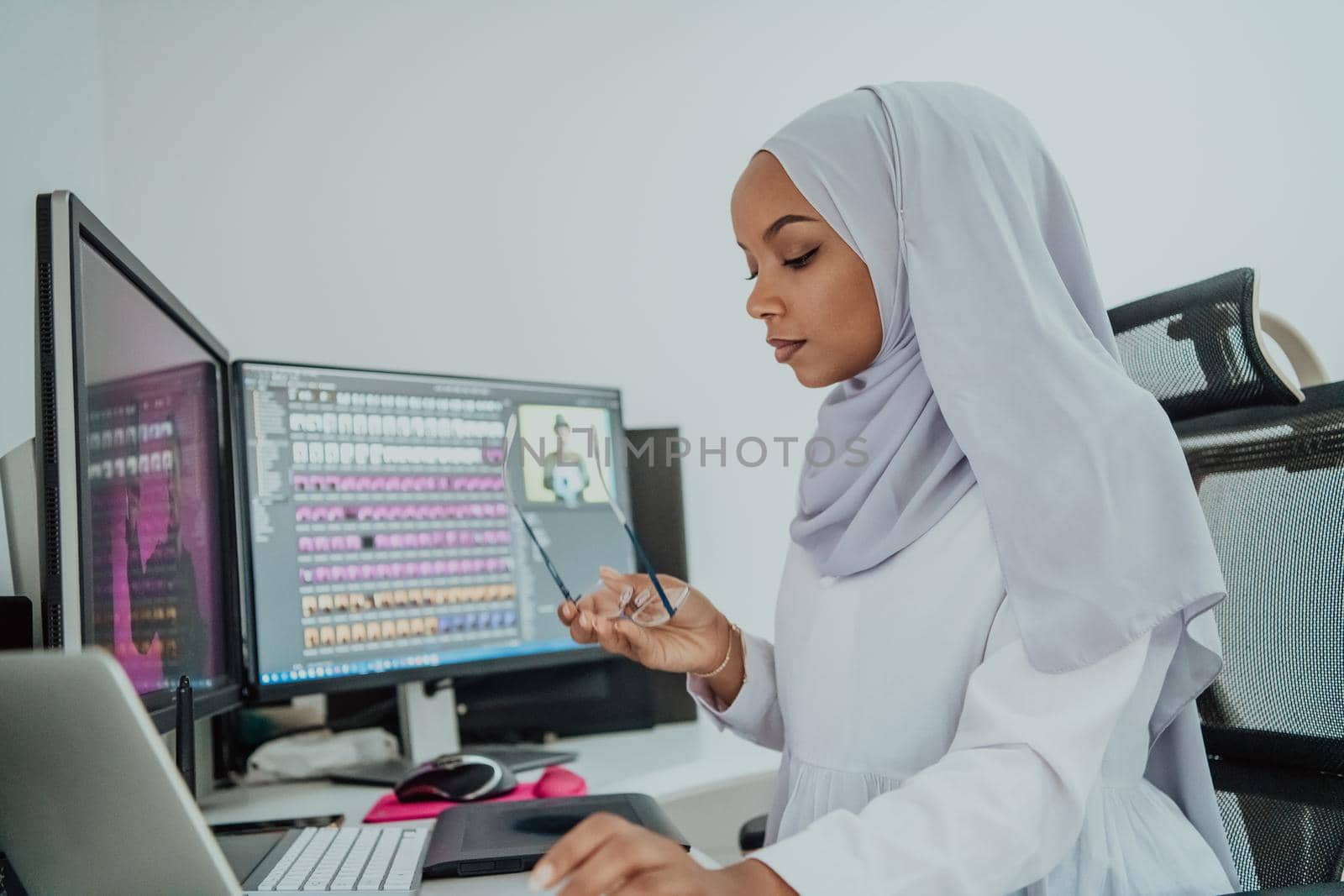 Young Afro-American modern Muslim businesswoman wearing a scarf in a creative bright office workplace with a big screen. High-quality photo