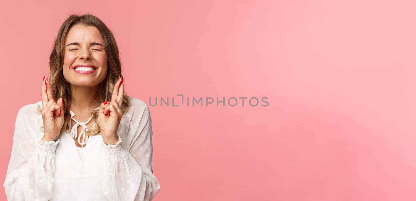 Portrait of excited hopeful blond girl making wish crossed fingers for good luck, close eyes and smiling putting all effort into pray, pleading for dream come true, anticipating over pink background by Benzoix