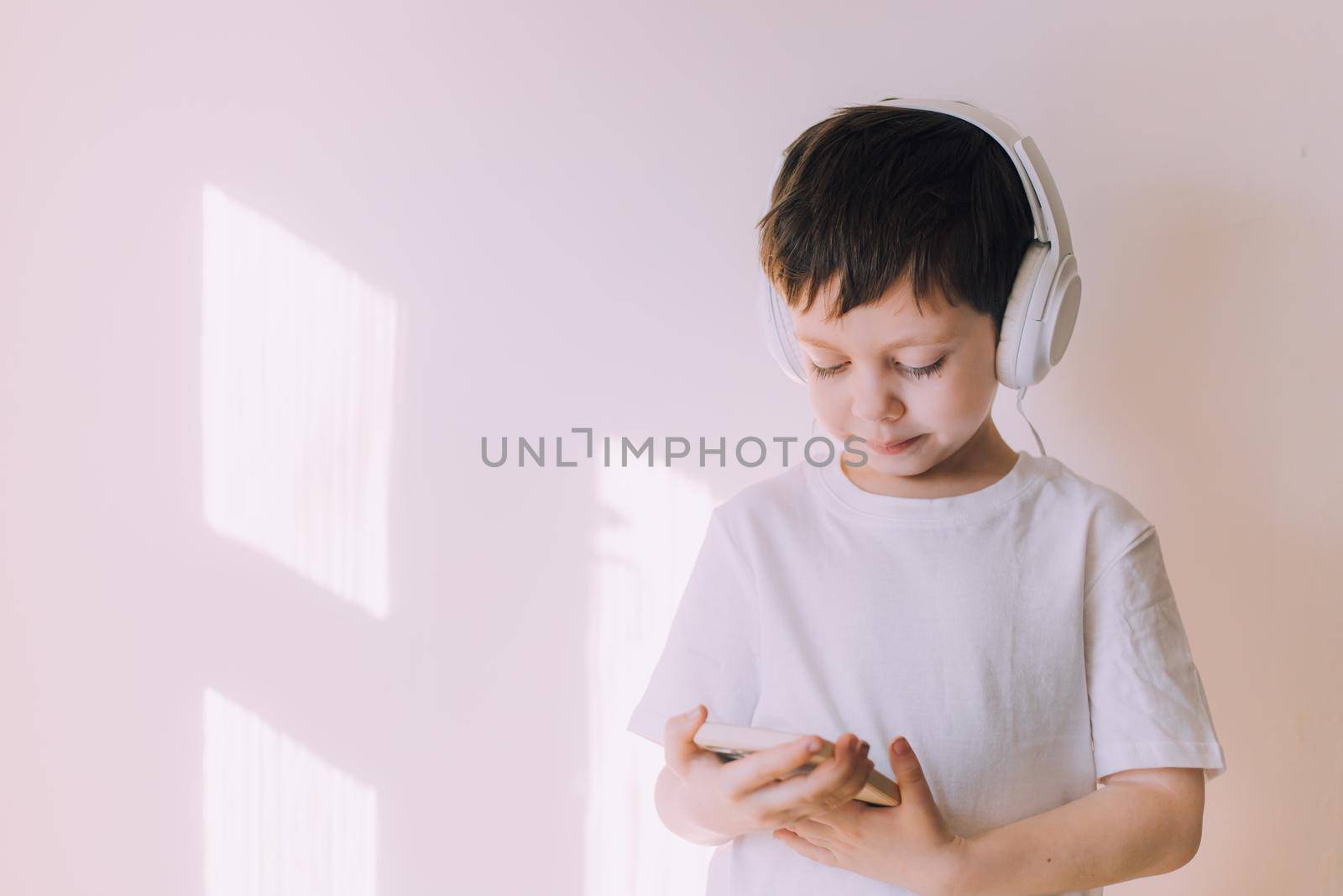 The boy listens to music with lifestyle headphones . Modern technologies. Kids and gadgets. Music for children. Modern children. Smartphones in children. Copy space. White background.