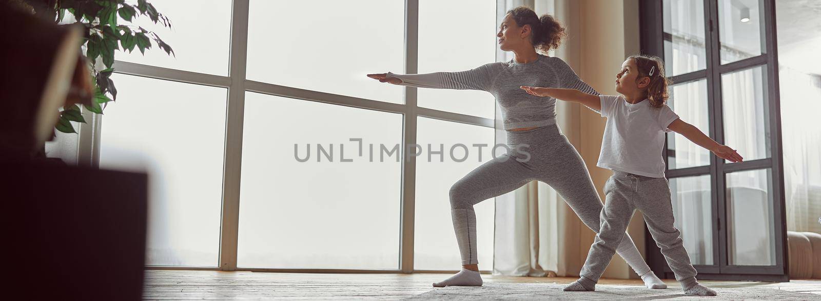 Low angle of calm woman standing in asana while her daughter is repeating after her