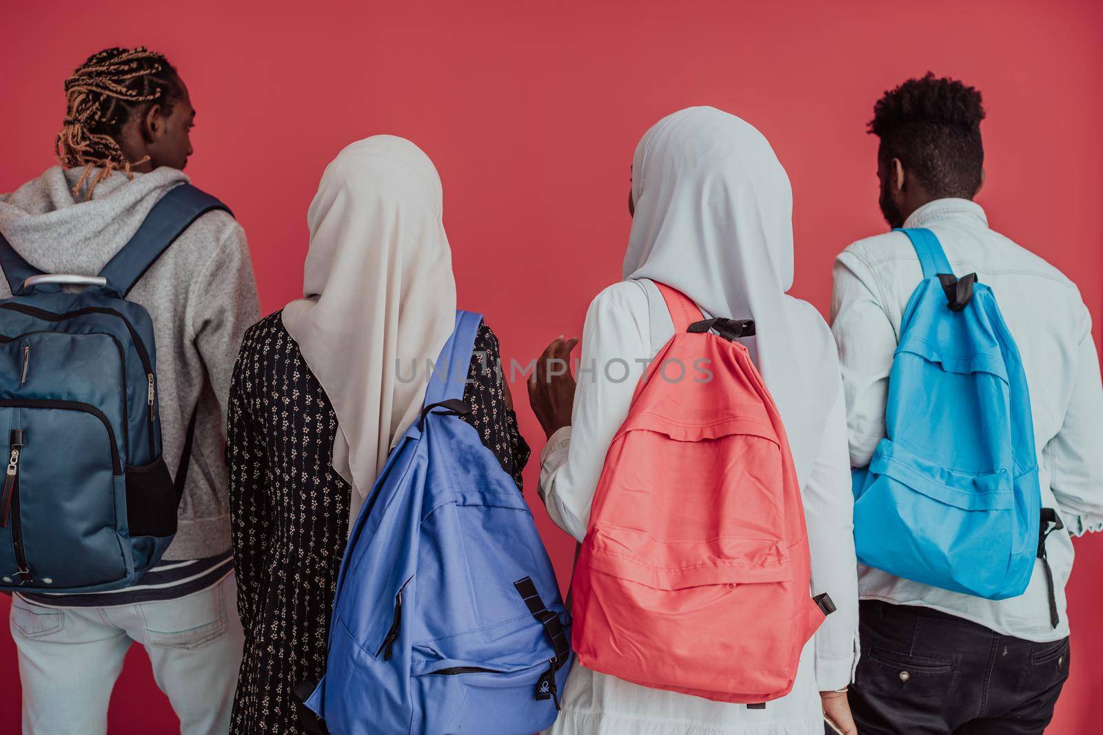 A group of African Muslim students with backpacks posing on a pink background. the concept of school education. by dotshock