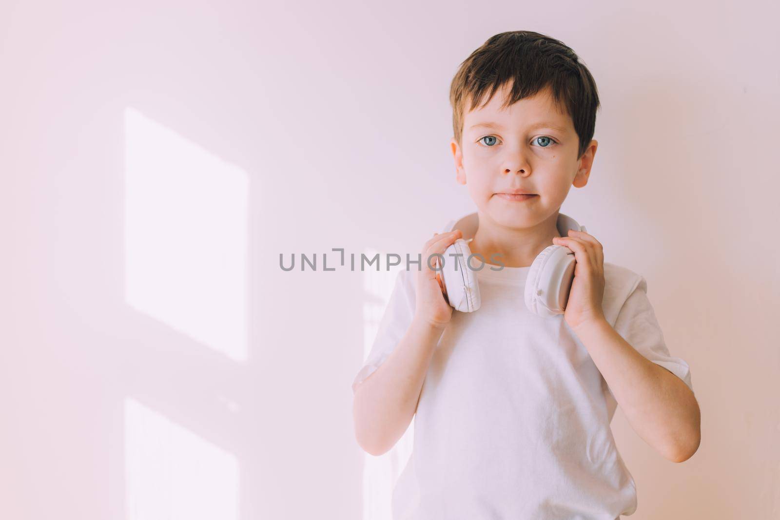 The boy listens to music with lifestyle headphones . Modern technologies. Kids and gadgets. Music for children. Modern children. Smartphones in children. Copy space. White background.