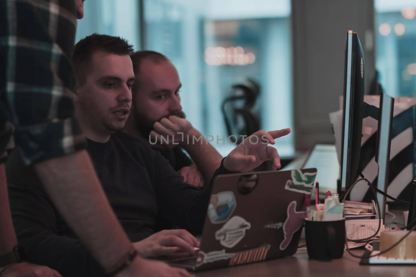 A photo of three men staring intently at a computer while sitting in a modern office. Selective focus by dotshock