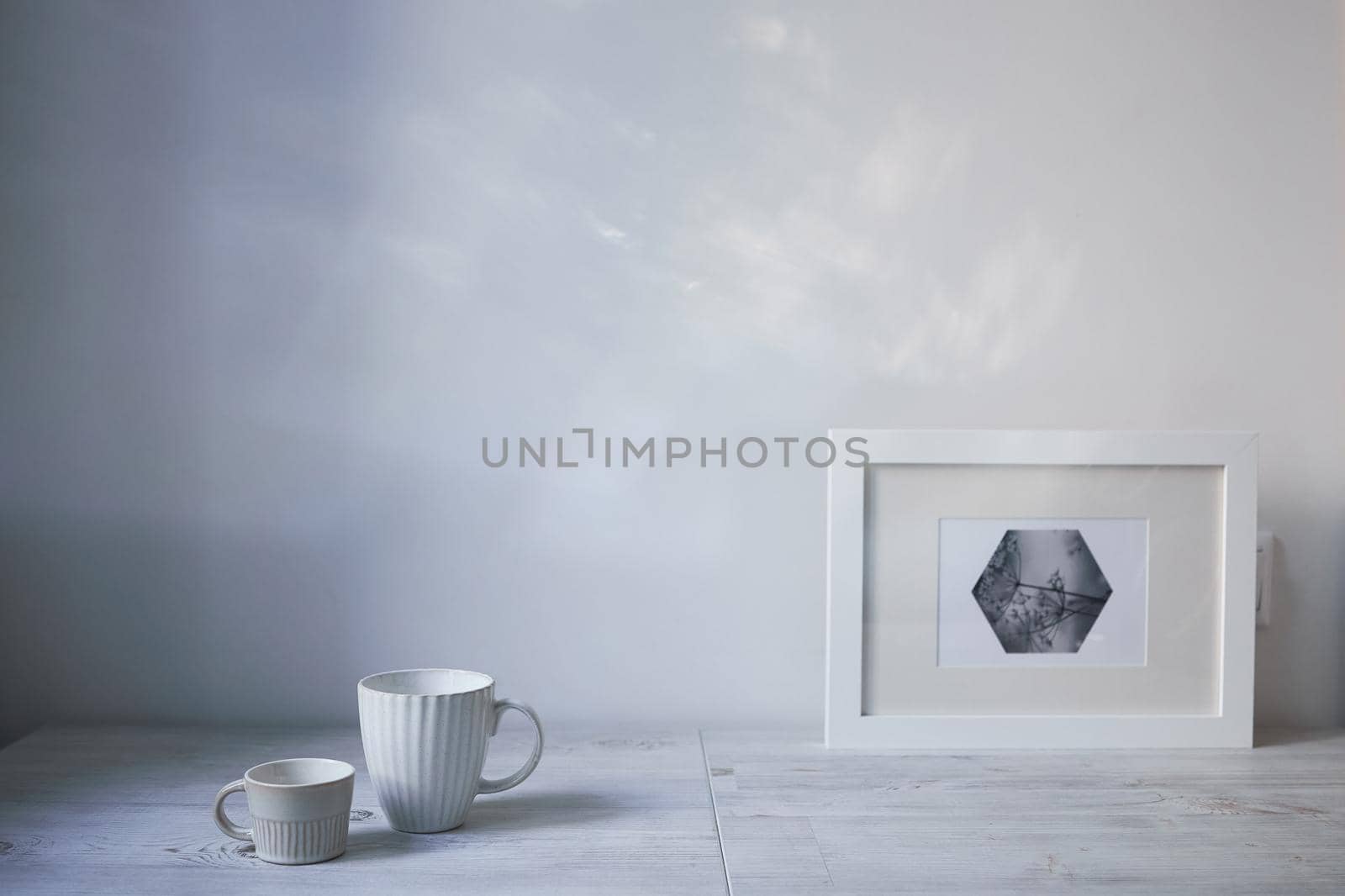 Scandinavian style. Interior Design. A white cup of different size, a frame for a photo are on the table. Empty space for text