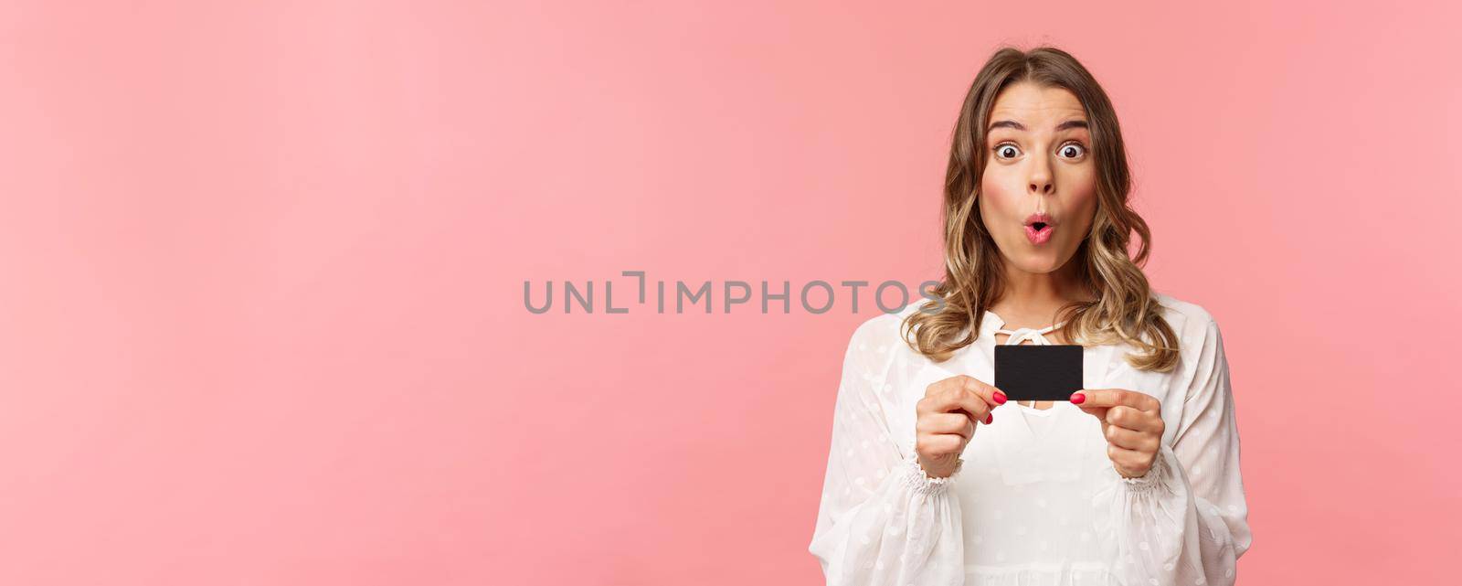 Close-up portrait of excited and amused young girl describe new features of her bank, received new credit card, say wow, folding lips thrilled and amazed, standing pink background by Benzoix