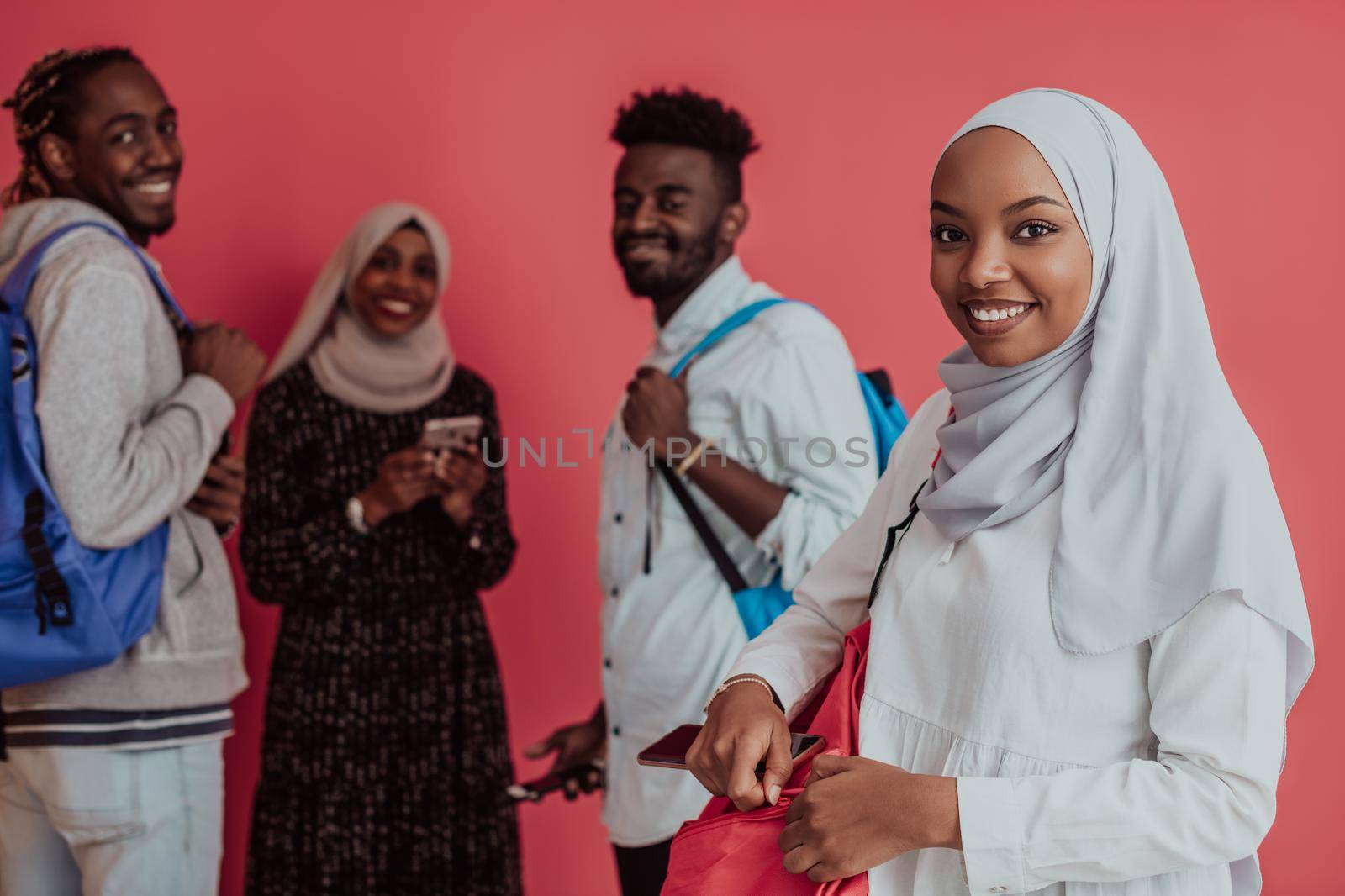 A group of African Muslim students with backpacks posing on a pink background. the concept of school education. High-quality photo