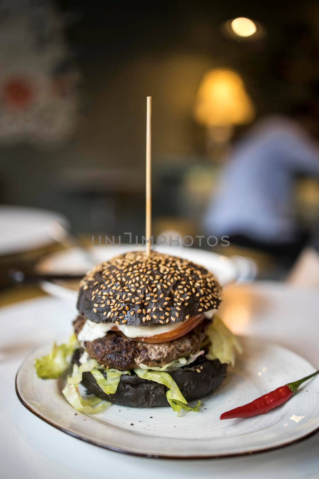 Black flour burger on a plate with red hot peppers on a plate