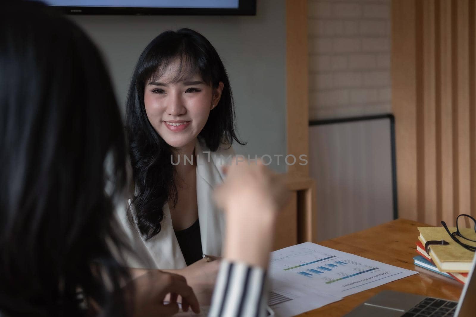 Two diverse businesswomen discussing business project working together in office.