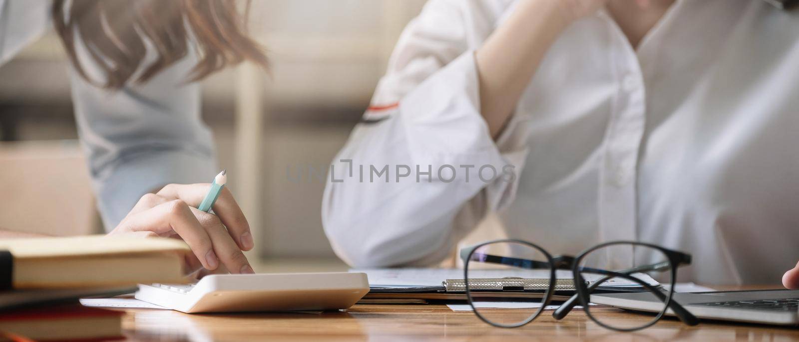 Business team using a calculator and laptop computer to calculate the numbers in a office by nateemee