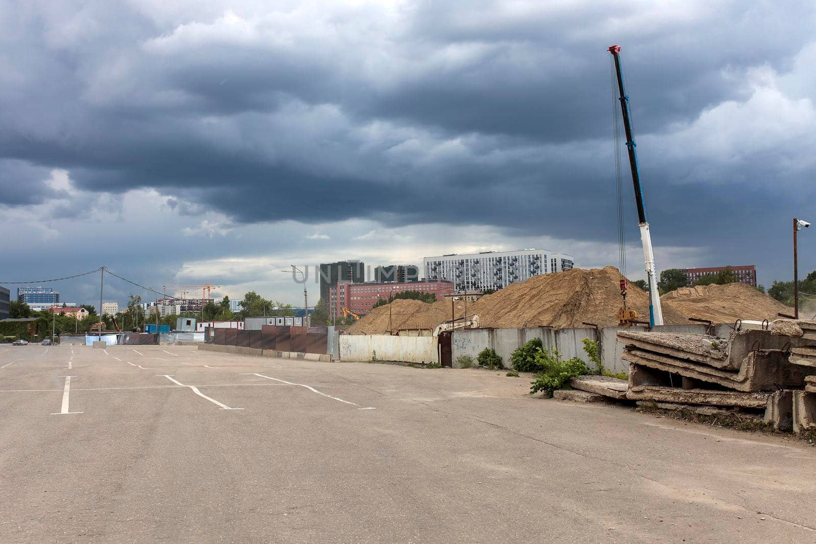 Long factory pipes lie on the ground against the backdrop of a residential area under construction by elenarostunova