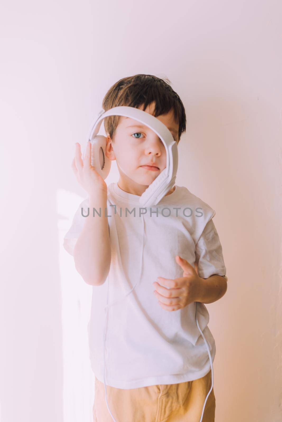 The boy listens to music with lifestyle headphones . Modern technologies. Kids and gadgets. Music for children. Modern children. Smartphones in children. Copy space. White background.