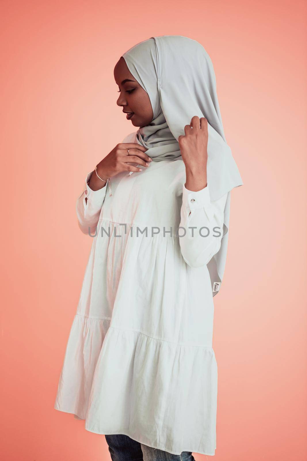 Portrait of young modern muslim afro beauty wearing traditional islamic clothes on plastic pink background. Selective focus. High quality photo