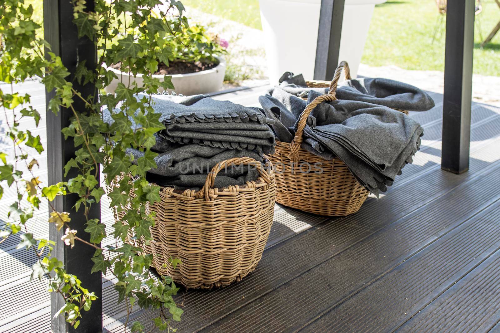 Wicker baskets with gray woolen blankets in case of bad weather on the restaurant terrace by elenarostunova