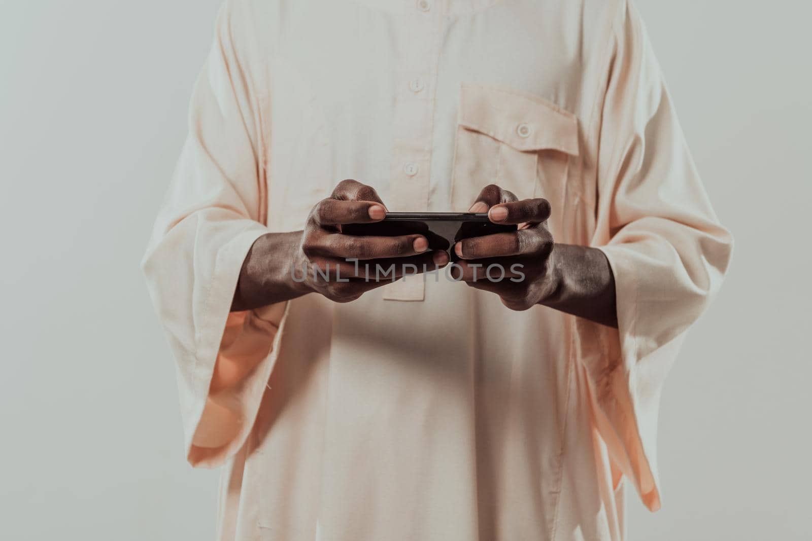 African man using smartphone and wearing traditional Sudan clothes. by dotshock