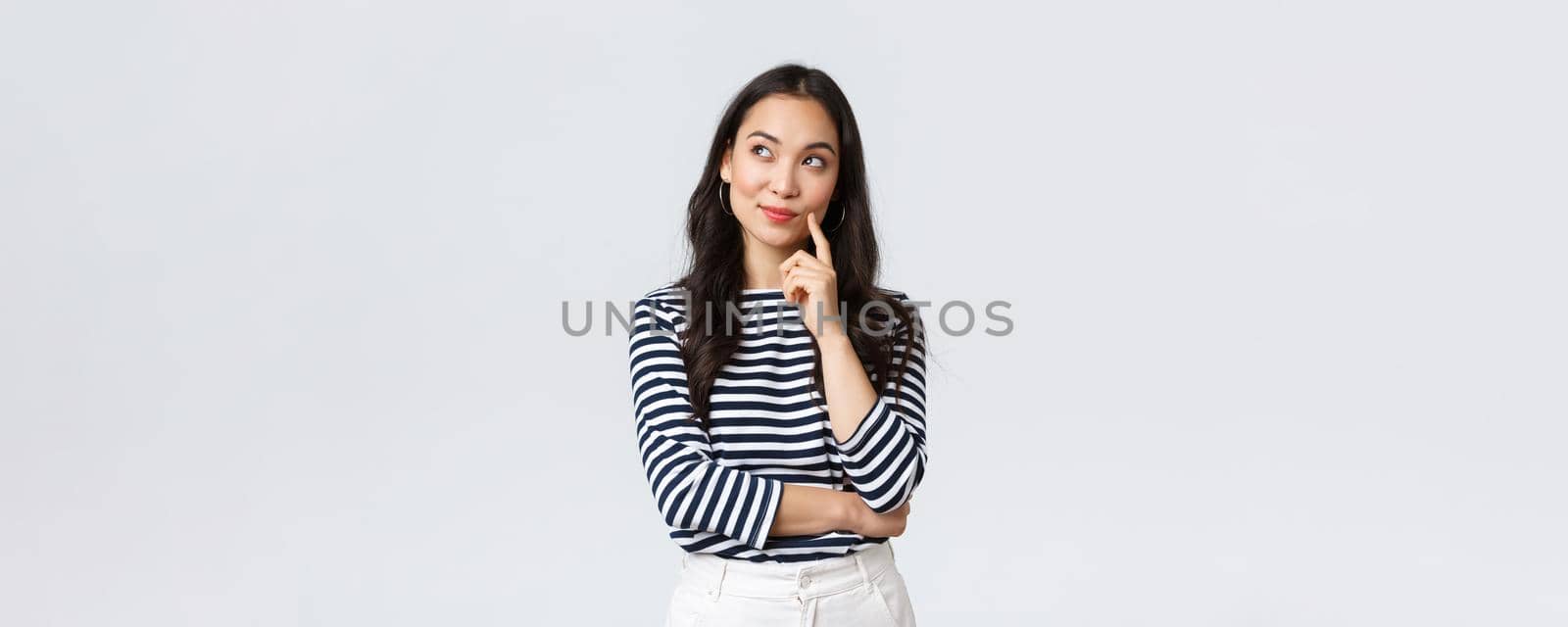 Lifestyle, people emotions and casual concept. Thoughtful stylish young woman smiling pleased, dreaming or imaging perfect plan, have interesting idea, thinking and looking upper left corner.