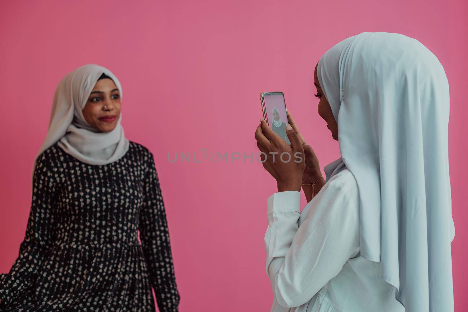 Two african american women in hijab poses for social media in the studio. Selective focus. High quality photo
