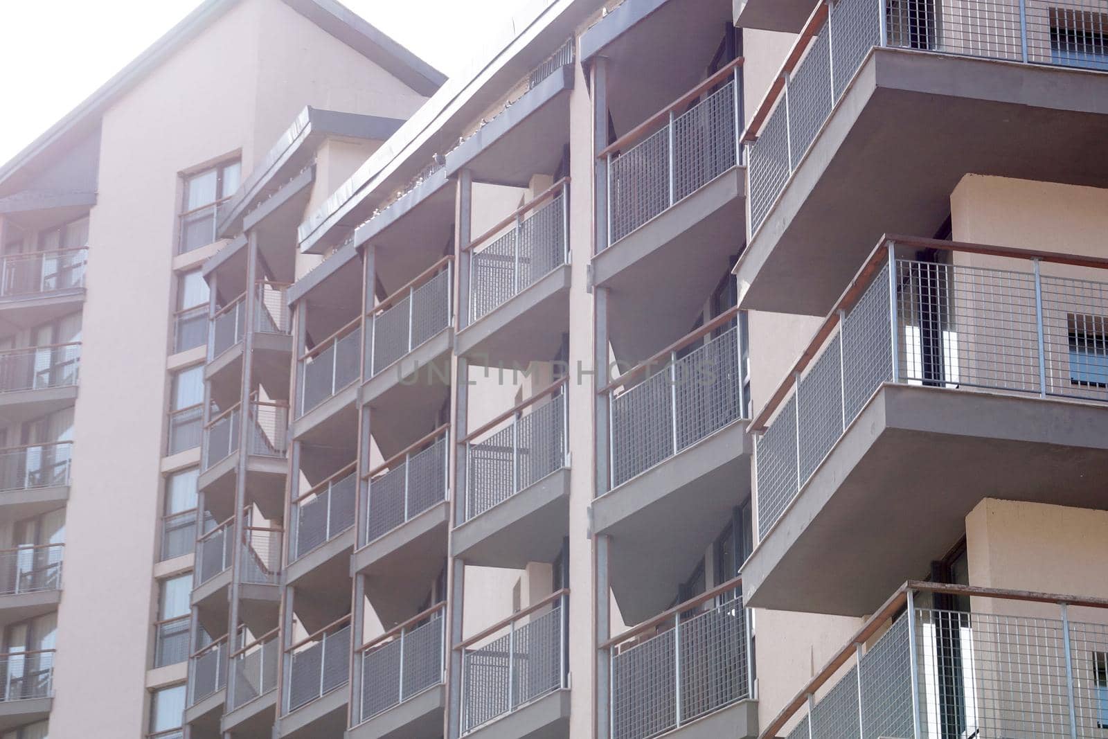 facade of modern residential apartment building with glass balconies in sunlight by Annado