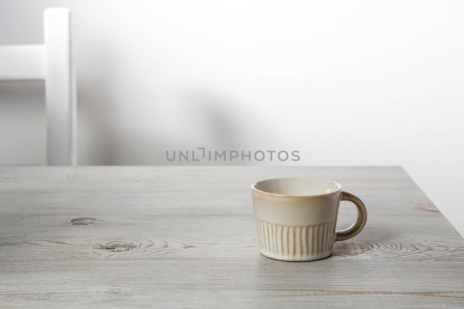 Small coffee cup is on a beige table. Place for text by elenarostunova