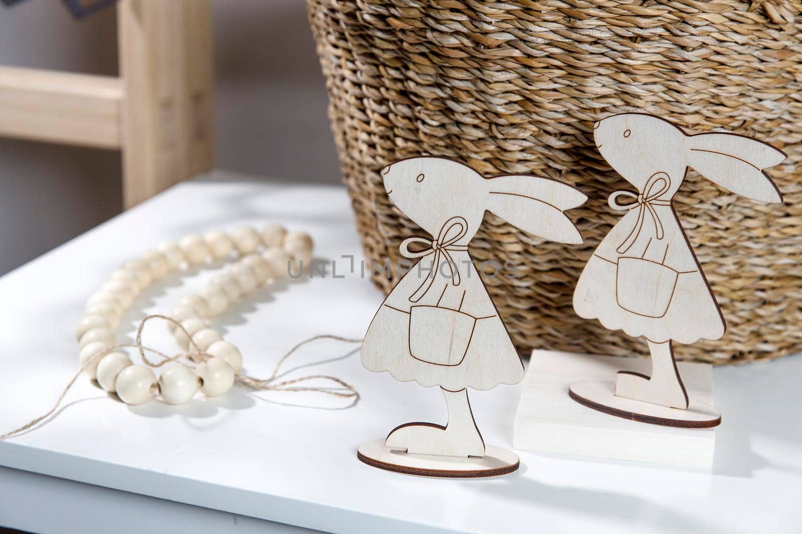 Interior decoration for Easter. A rag rabbit peeks out of a wicker willow basket on the table. by elenarostunova