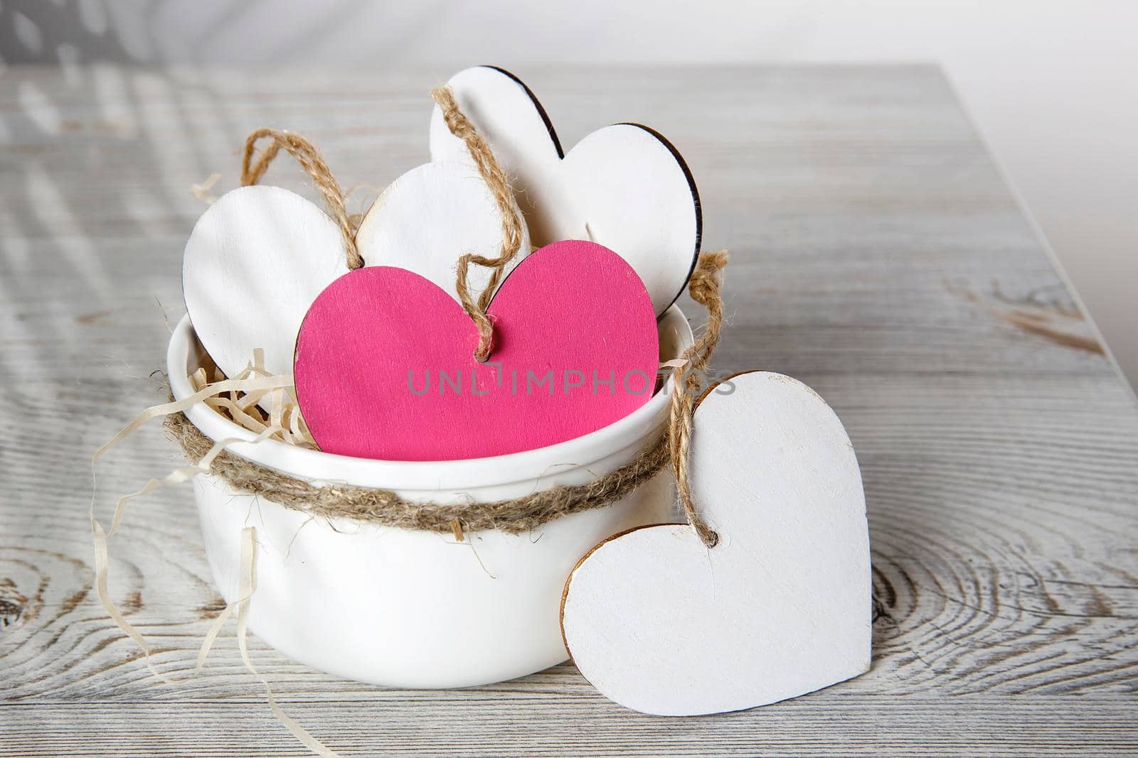 White and red wooden hearts in a ceramic bowl filled with paper. Place for your text by elenarostunova