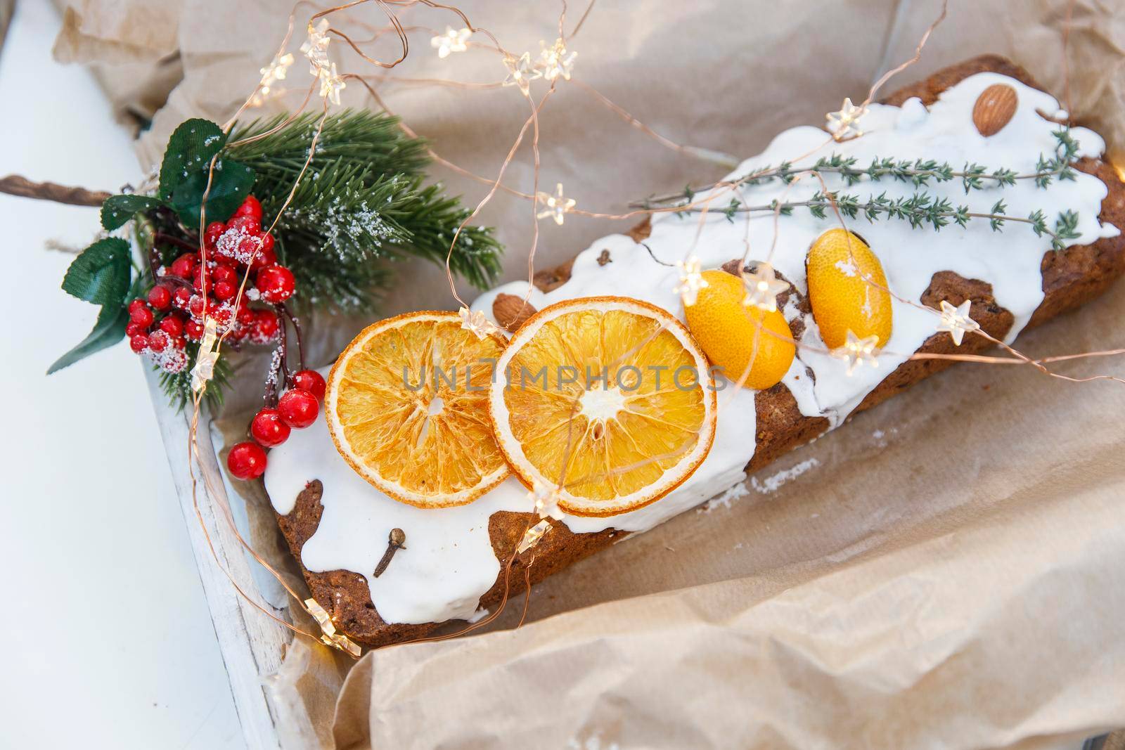 Traditional christmas cupcake garnished with dry orange wedges, clove spice and rosemary sprig in craft paper by elenarostunova