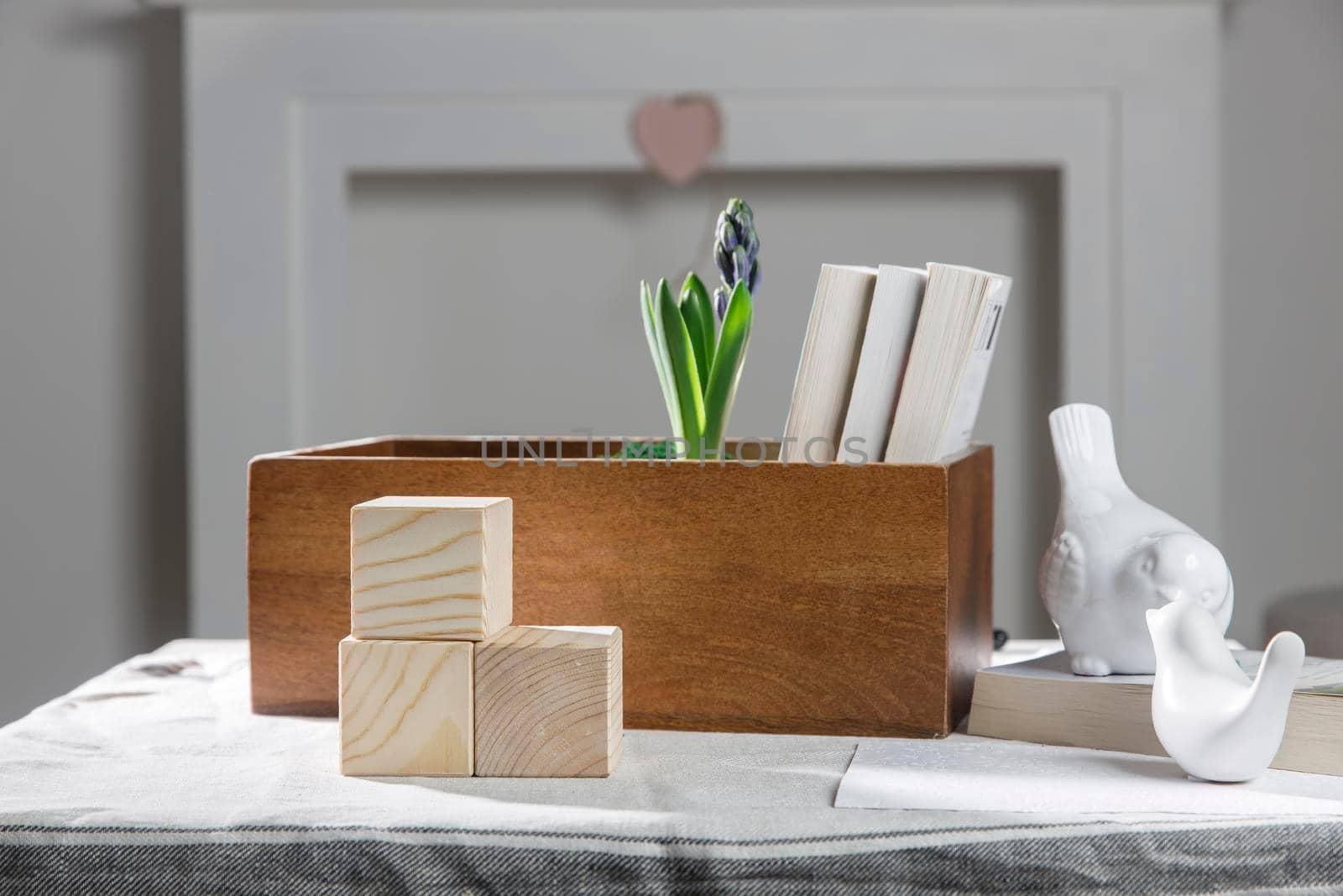 Wooden container with books, three cubes on the table against the background of a white fireplace. Place for text. Valentine's Day