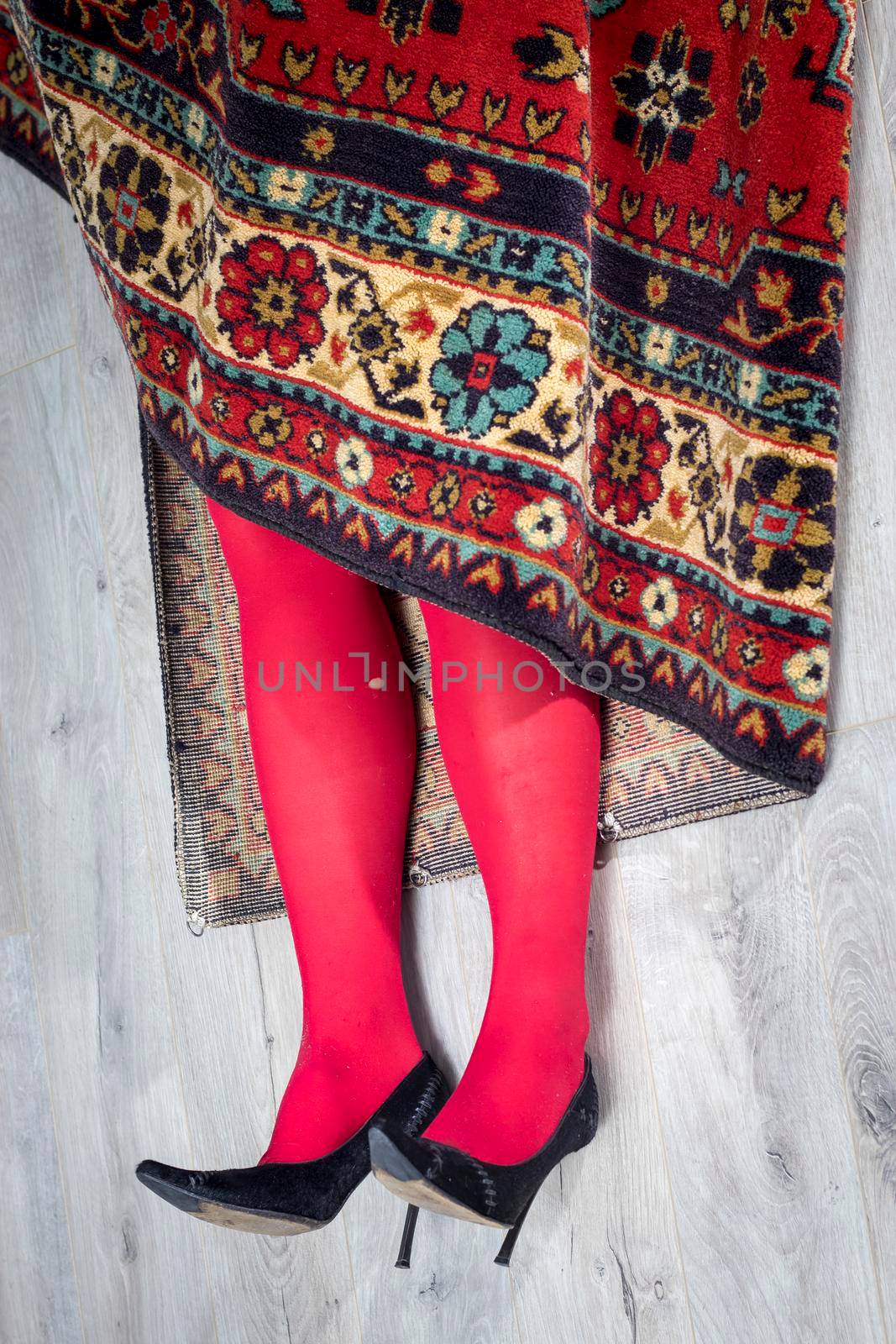 Red female legs in torn tights stick out of the carpet by elenarostunova