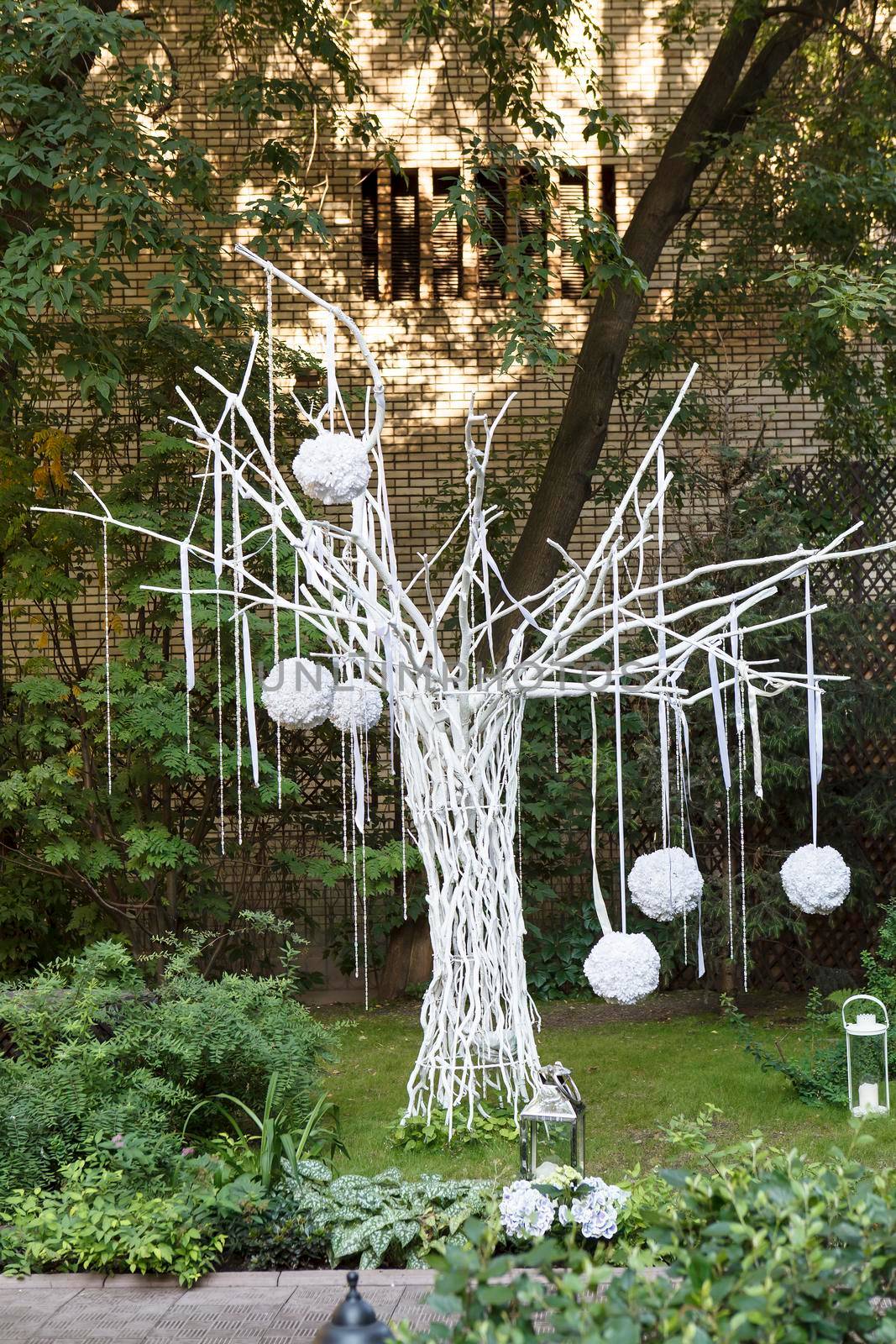 White painted tree with hanging balls, installation in the park. by elenarostunova