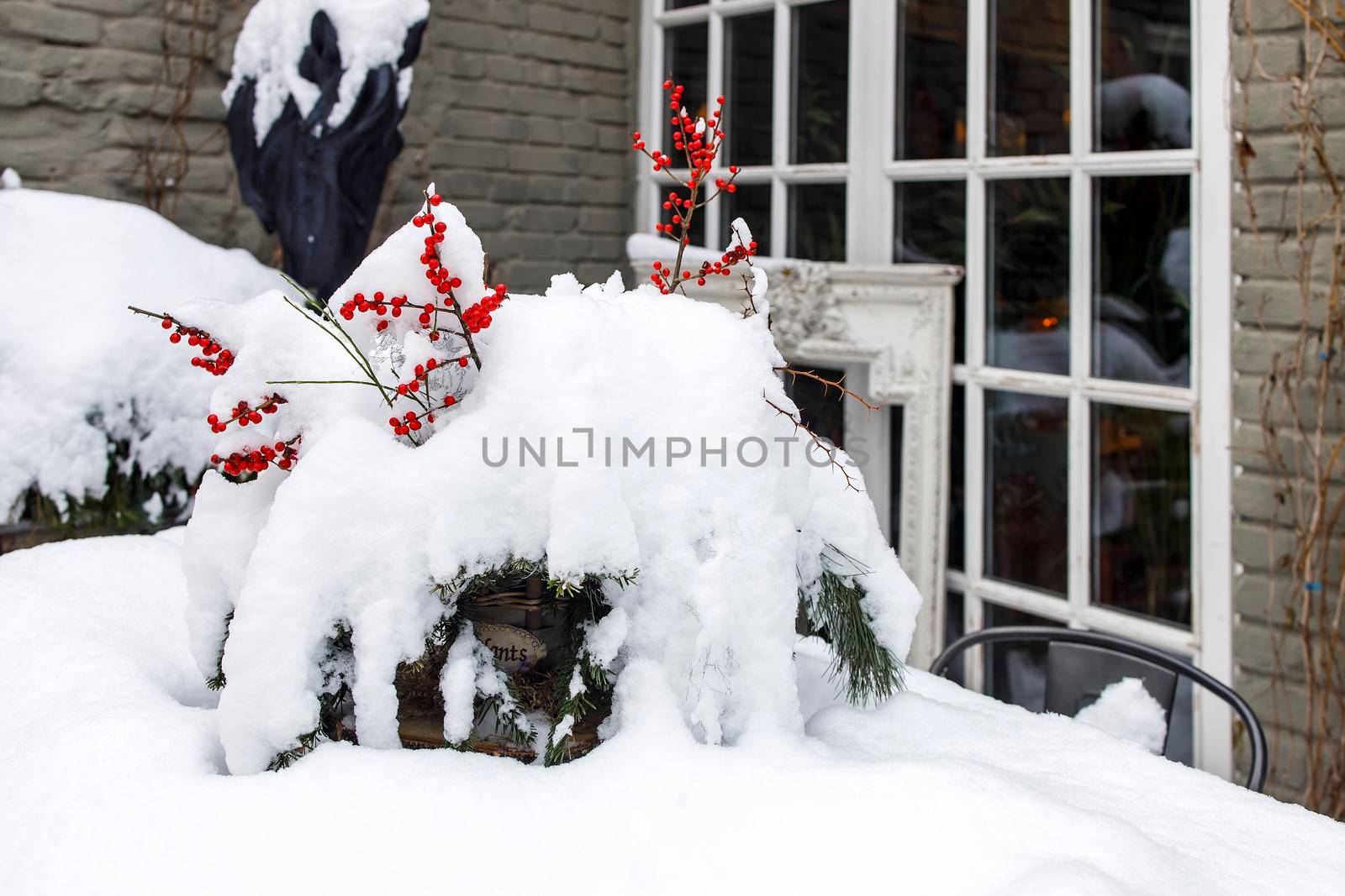 Snow-covered veranda, a table with a dried bouquet of branches with viburnum berries