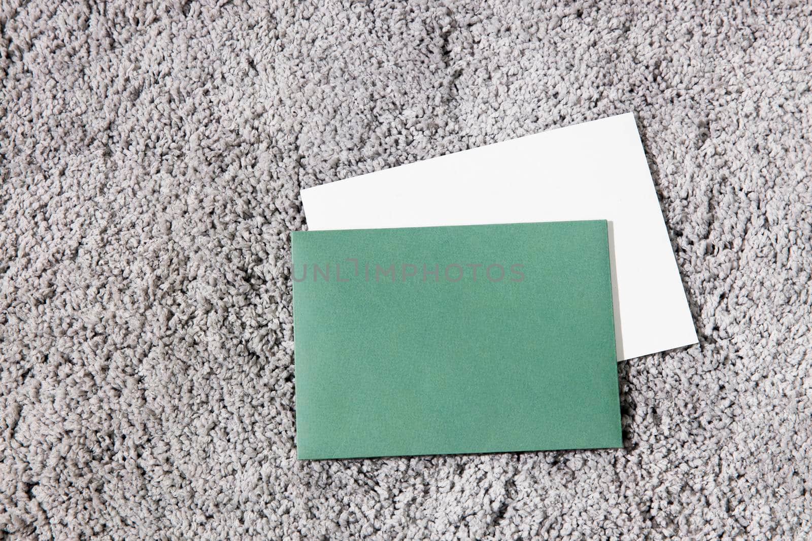 Green and white envelopes are on a gray fluffy surface. Concept for text.