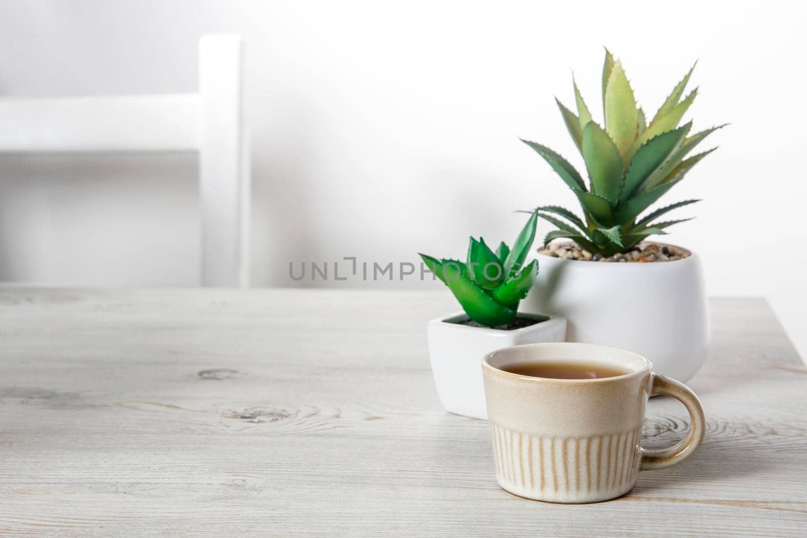Office desk wood table of the business work place, artificial plants and coffee cup with copy space on grey wooden table.